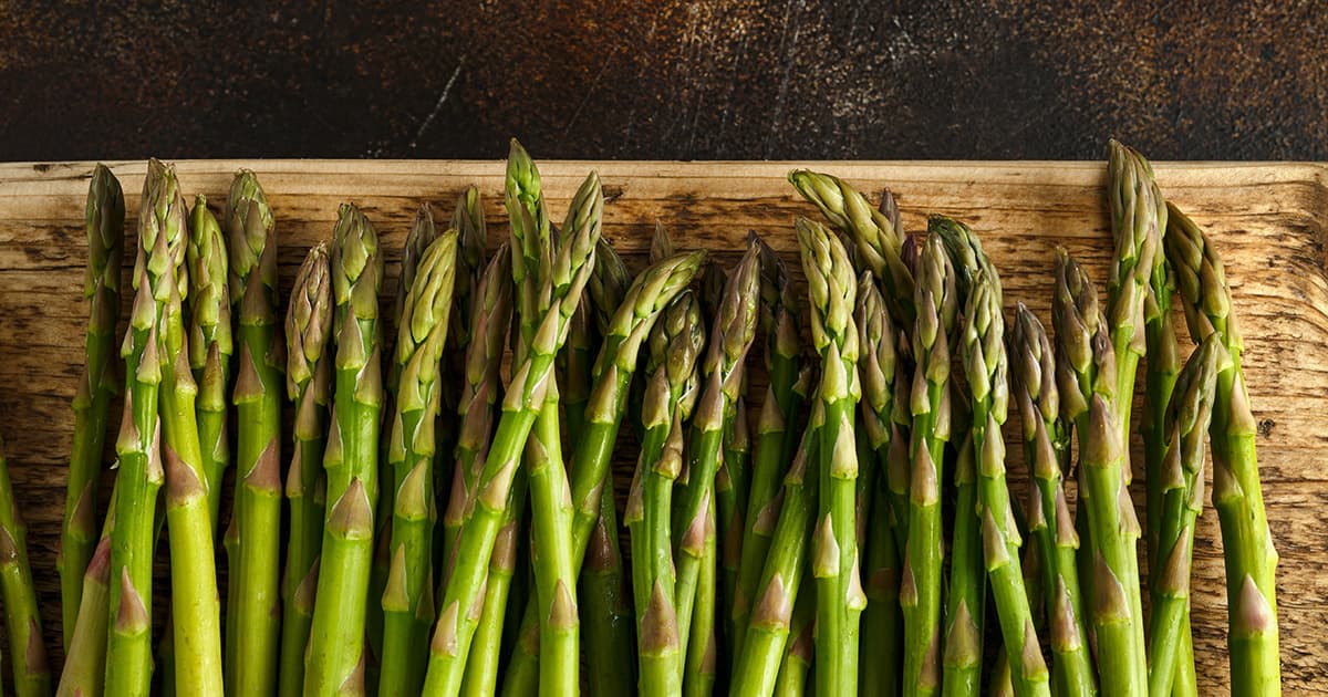 Freshly picked organic asparagus tips on wooden board